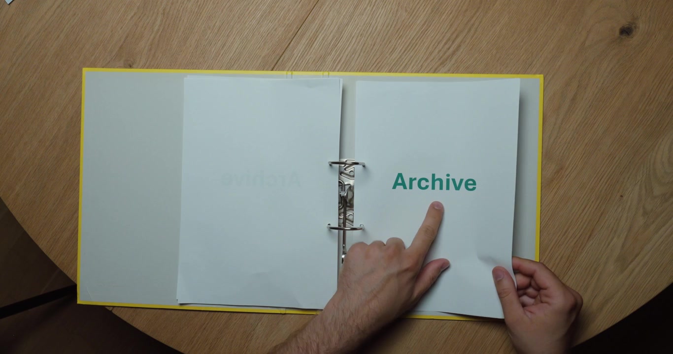 A person flips through a binder containing archived documents. Concept of document archiving, records management, long-term storage, and business documentation.