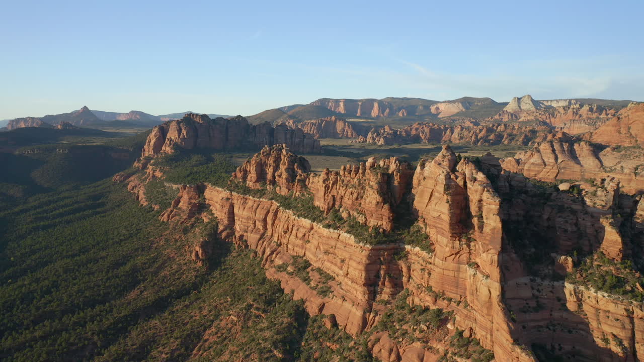 panorámica aérea a la derecha de las extensas montañas y valles anaranjados de utah que muestran paisajes impresionantes y escarpados del suroeste americano.