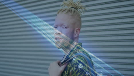 standing against corrugated metal, person with light hair wearing patterned shirt