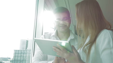 Happy-businesspeople-using-pad-by-the-window