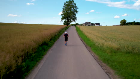 A-runner-running-uphill-off-road---drone-shot-from-behind