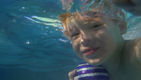 boy diving and coming up from water in the pool