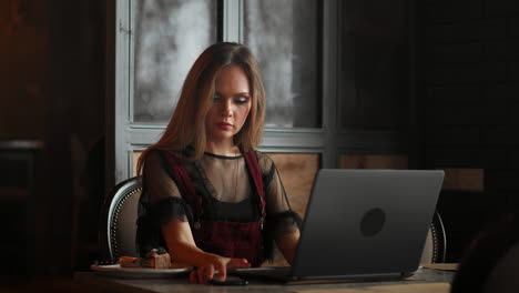 Happy-young-woman-drinking-coffee-and-using-tablet-computer-in-cafe