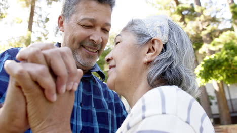 Happy-biracial-senior-couple-dancing-in-sunny-garden