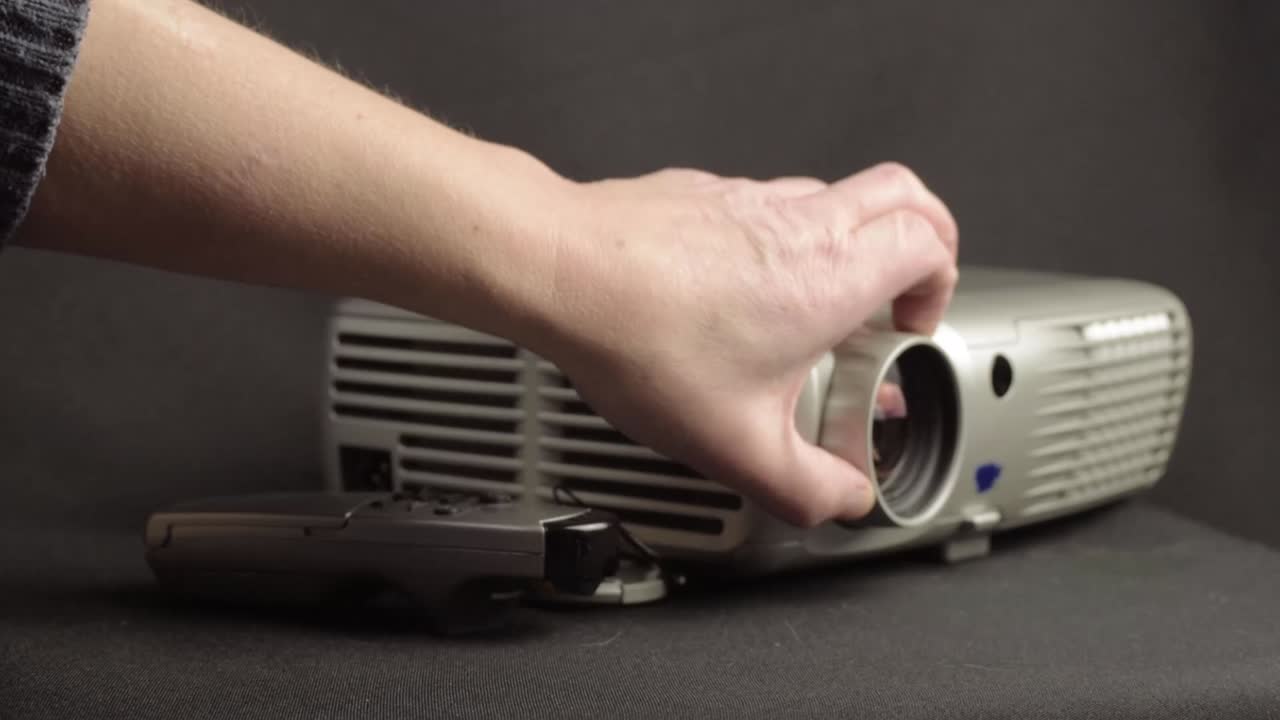 Hand using projector and remote control to prepare for presentation medium shot