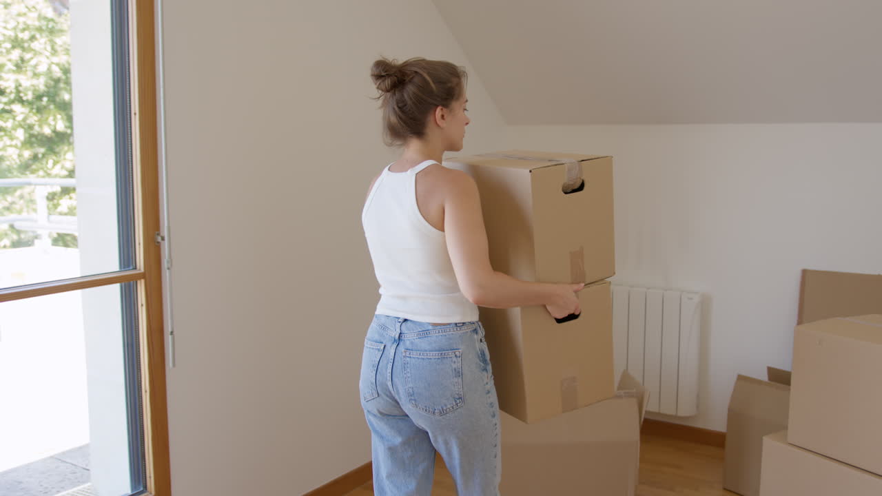 Tracking shot of woman carrying moving boxes to new apartment