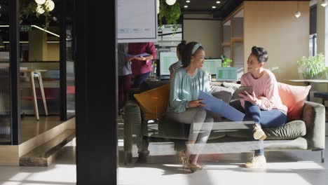 Diverse-business-people-sitting-with-documents-and-discussing-work-at-office