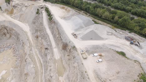 aerial view of a large quarry with heavy construction machinery and material piles