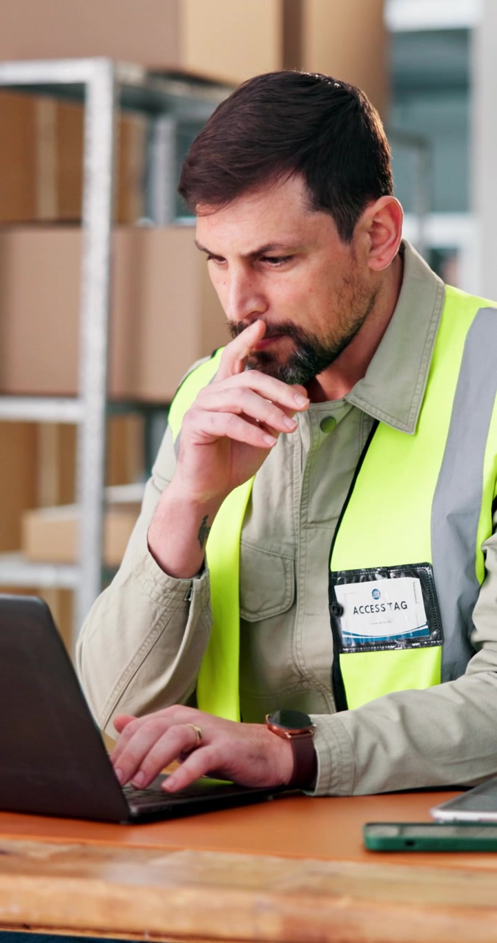 Warehouse Manager Working on Laptop in Distribution Center