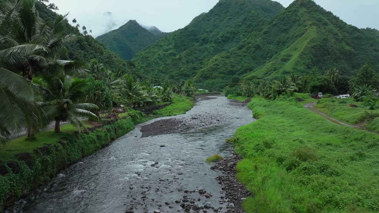 Teahupoo Tahiti French Polynesia aerial drone mountains morning grey gray raining fog season wet green grass palm trees end of the road Point Faremahora village town buildings island backwards slowly