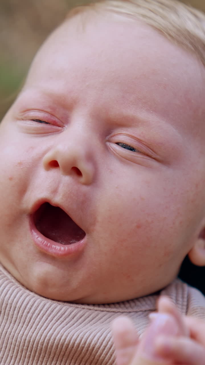 Lovely cute baby smiling adorable from mom's touch. Portrait of a Caucasian blonde infant close up. Vertical video
