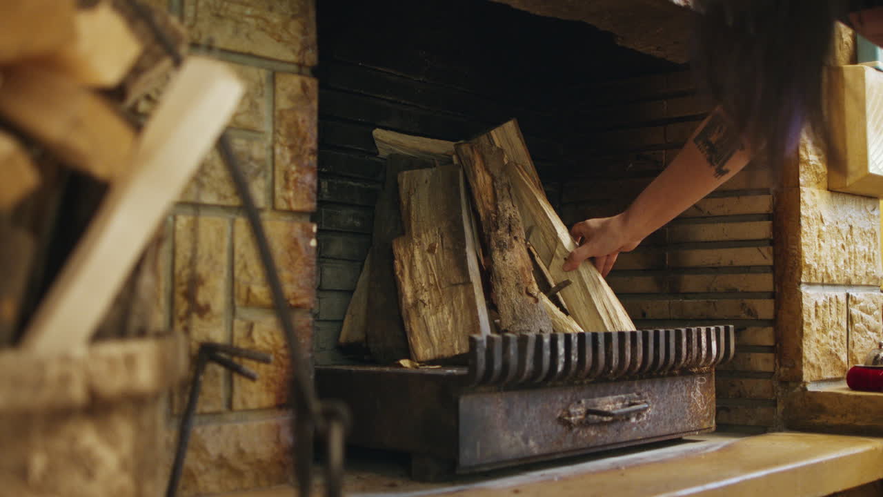 mujer poniendo y arreglando maderas para fogatas en una chimenea decorada con piedra para noches de invierno cálidas y acogedoras en cámara lenta