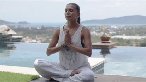 Relaxed-barefooted-lady-sitting-in-lotus-position-near-swimming-pool