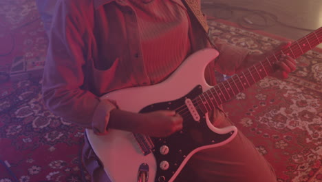 close up of an unrecognizable female musician playing electric guitar while kneeling on floor in recording studio