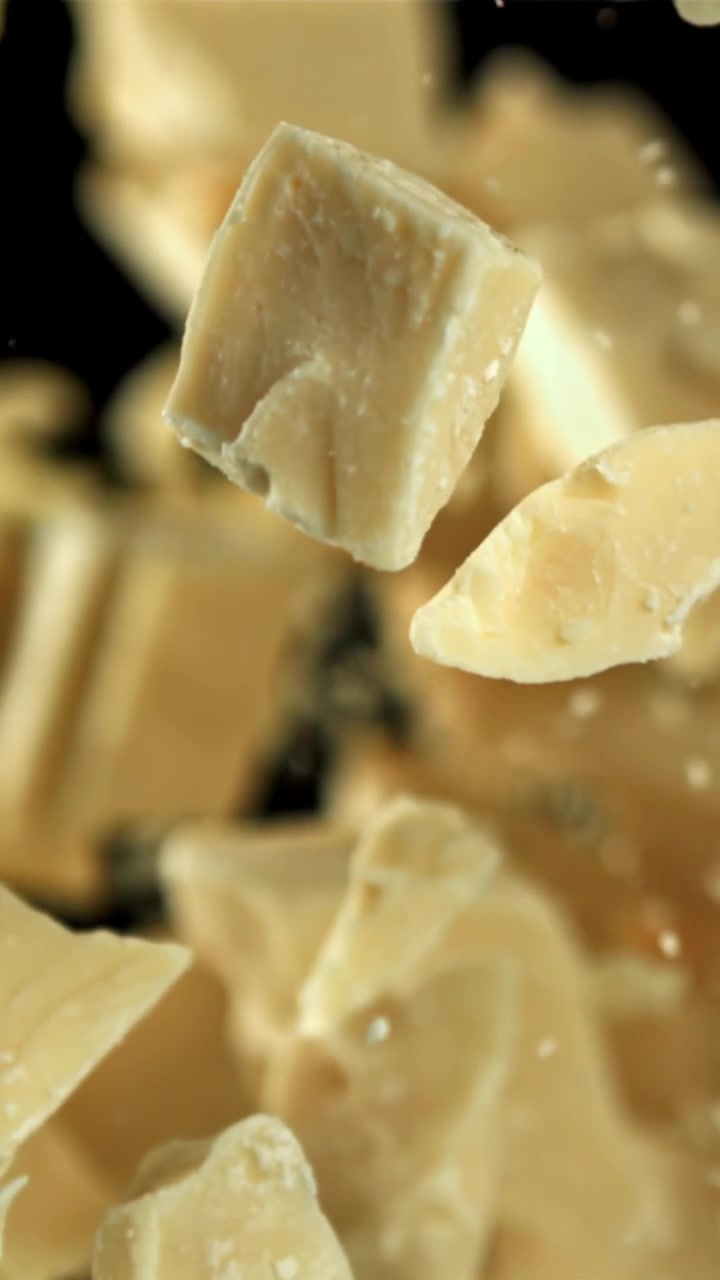 Chute de morceaux de chocolat blanc au ralenti sur fond noir