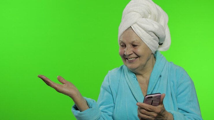 Anziana nonna in accappatoio. Anziana donna con smartphone che indica qualcosa
