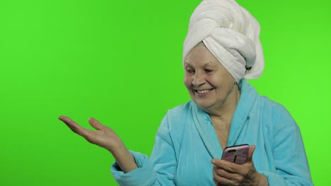 Abuela-Anciana-En-Bata-De-Baño.-Anciana-Con-Teléfono-Inteligente-Apuntando-A-Algo