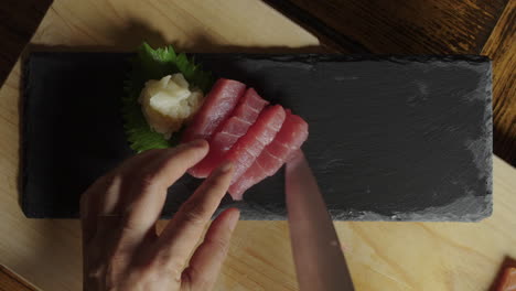 hands placing raw salmon and tuna on slate serving patter