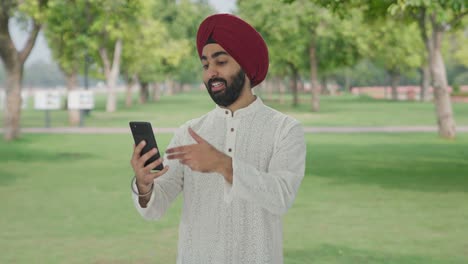 hombre indio sikh feliz hablando en video llamada en el parque