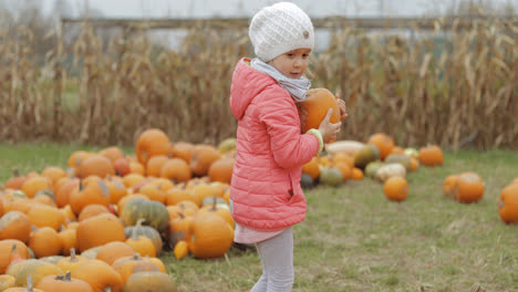 Girl-playing-with-pumpkins-in-garden