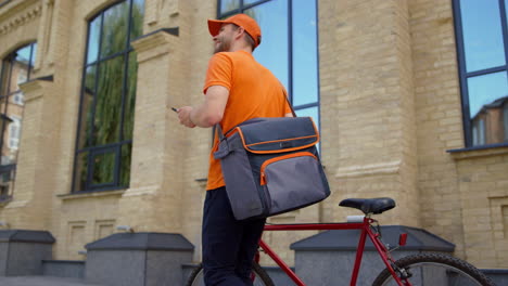 Mensajero-Acercándose-A-La-Bicicleta-Con-Teléfono-Móvil.