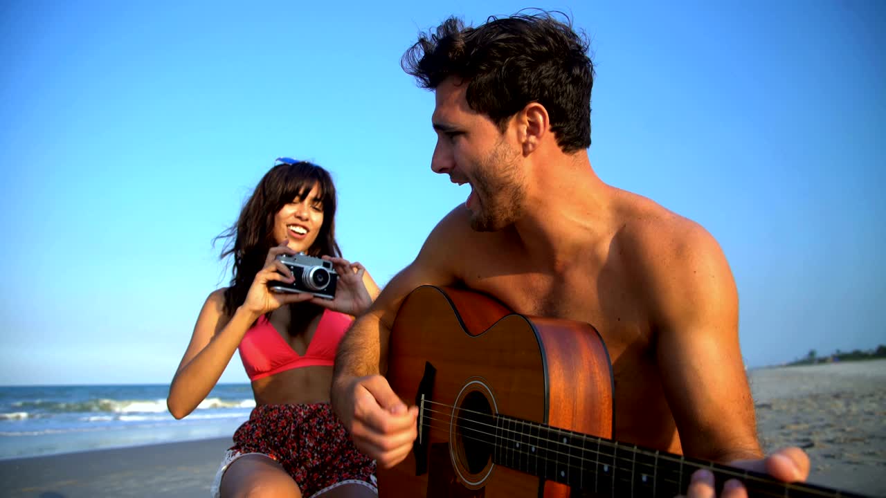 mujer hispana tomando fotos hombre caucásico tocando la guitarra