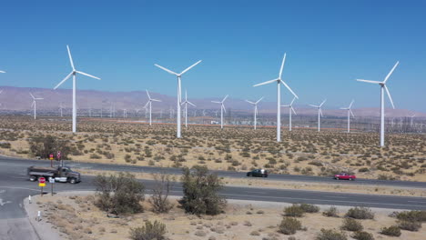 renewable white windmill turbine farm by western america countryside expressway with rotating onshore propellers generating green energy on bright blue sunny sky day, aerial profile