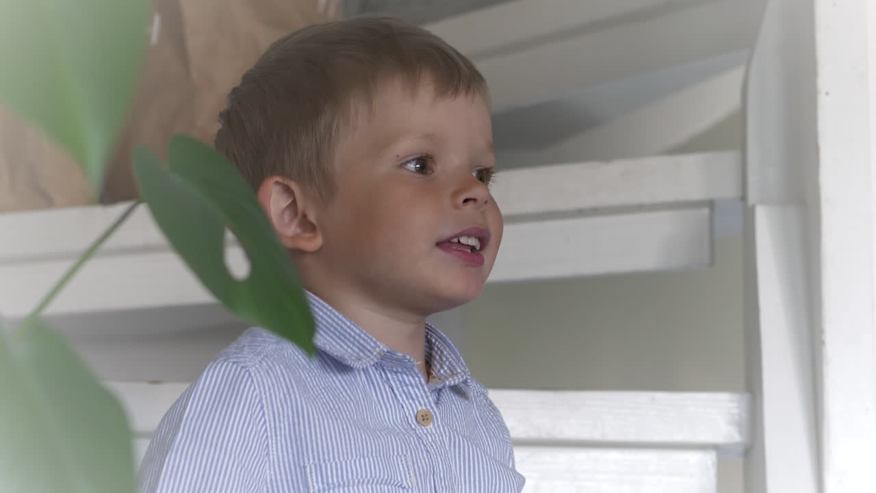 Young boy kid sitting on white staircase and looking into home interior