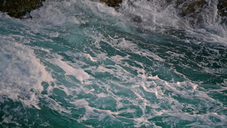 olas espumosas salpicando en el acantilado naturaleza de cerca. agua salada del mar chocando contra las rocas