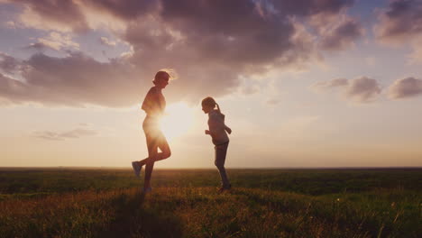 Silhouette-Of-A-Young-Woman-With-A-Child-Doing-Fitness-In-Nature-1