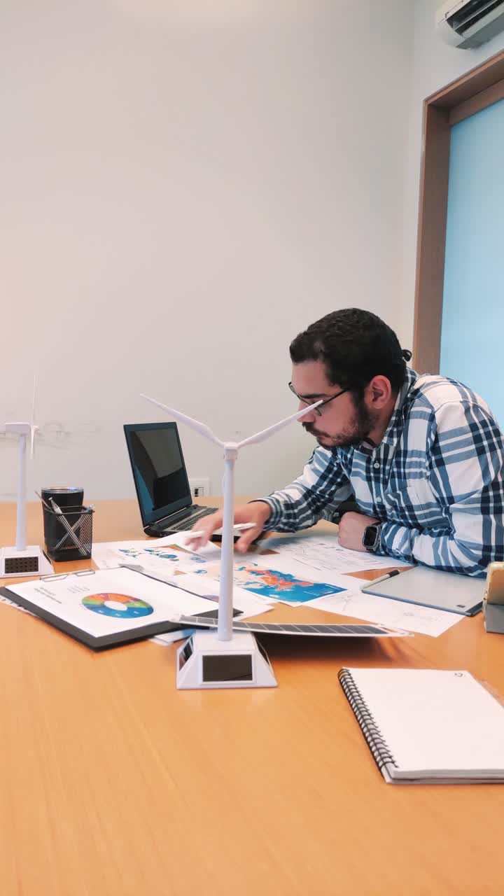 Professional Man Working at a Large Desk with Renewable Energy Models