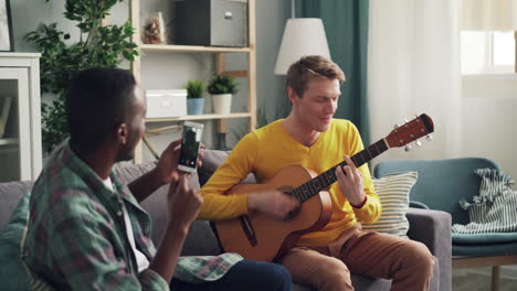 two men playing guitar and recording a video