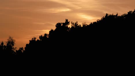 Asombroso-Lapso-De-Tiempo-Del-Cielo-Vespertino-O-Matutino-Con-Nubes-Naranjas-Y-Amarillas-Sobre-El-Bosque