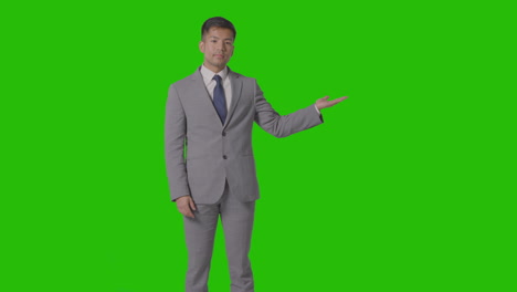 three quarter length shot of businessman in suit presenting or showing against green screen 3