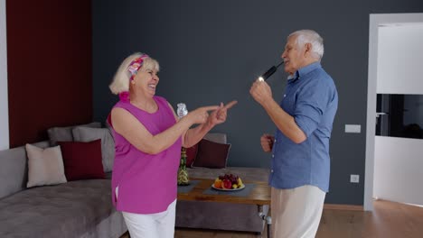 Pareja-Mayor-Bailando-Riéndose-En-Casa.-Abuelos-Relajándose-Divirtiéndose-Celebrando-Aniversario