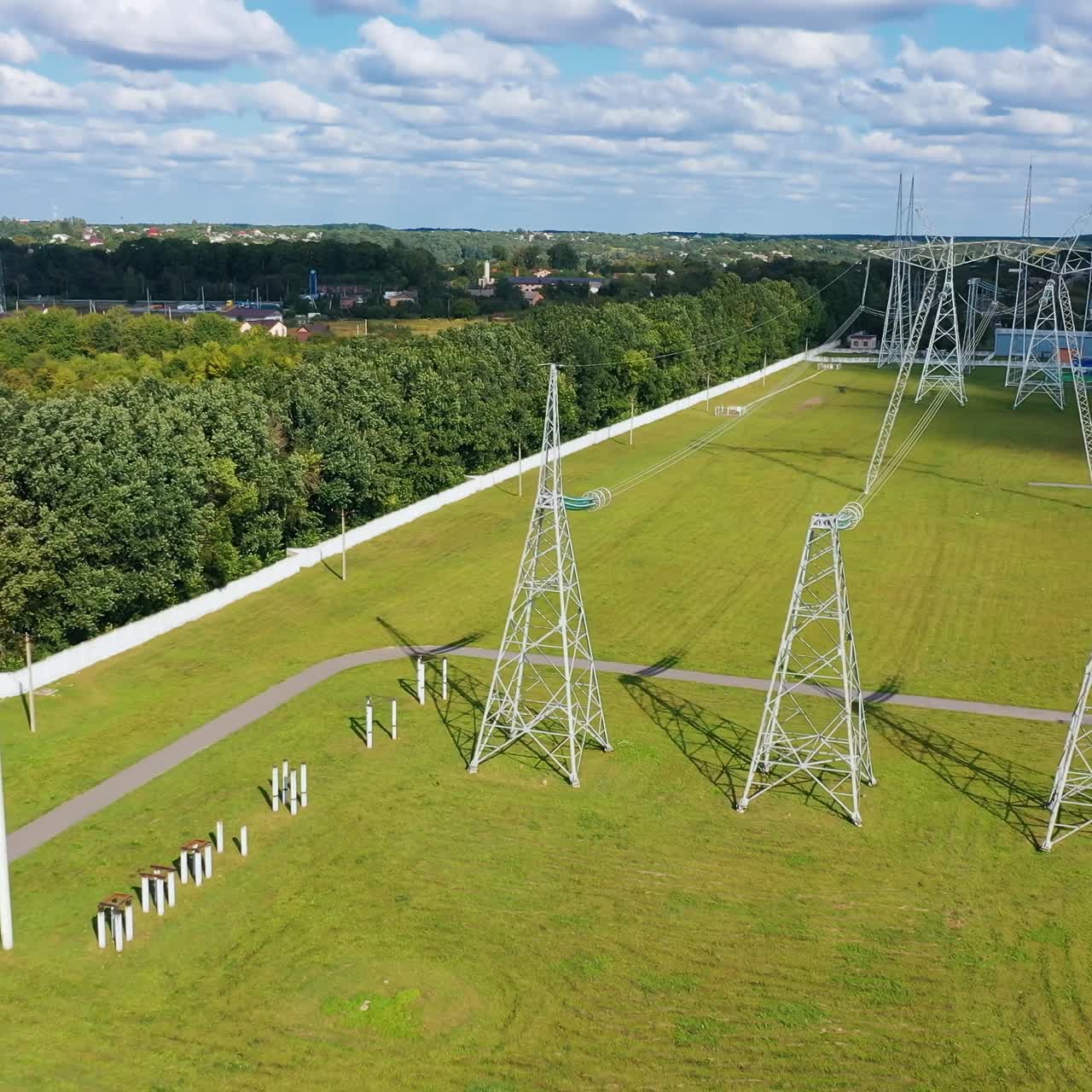 Panoramic view on a field with electric towers. High- voltage power lines with wires on the background of green nature in rural place