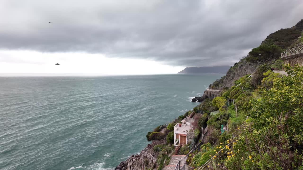 이탈리아의 리오마지오레 마을 근처의 바다 지평선과 거친 해안선을 내려다보며 이 해안 지역의 야생의 아름다움과 극적인 풍경을 포착합니다.