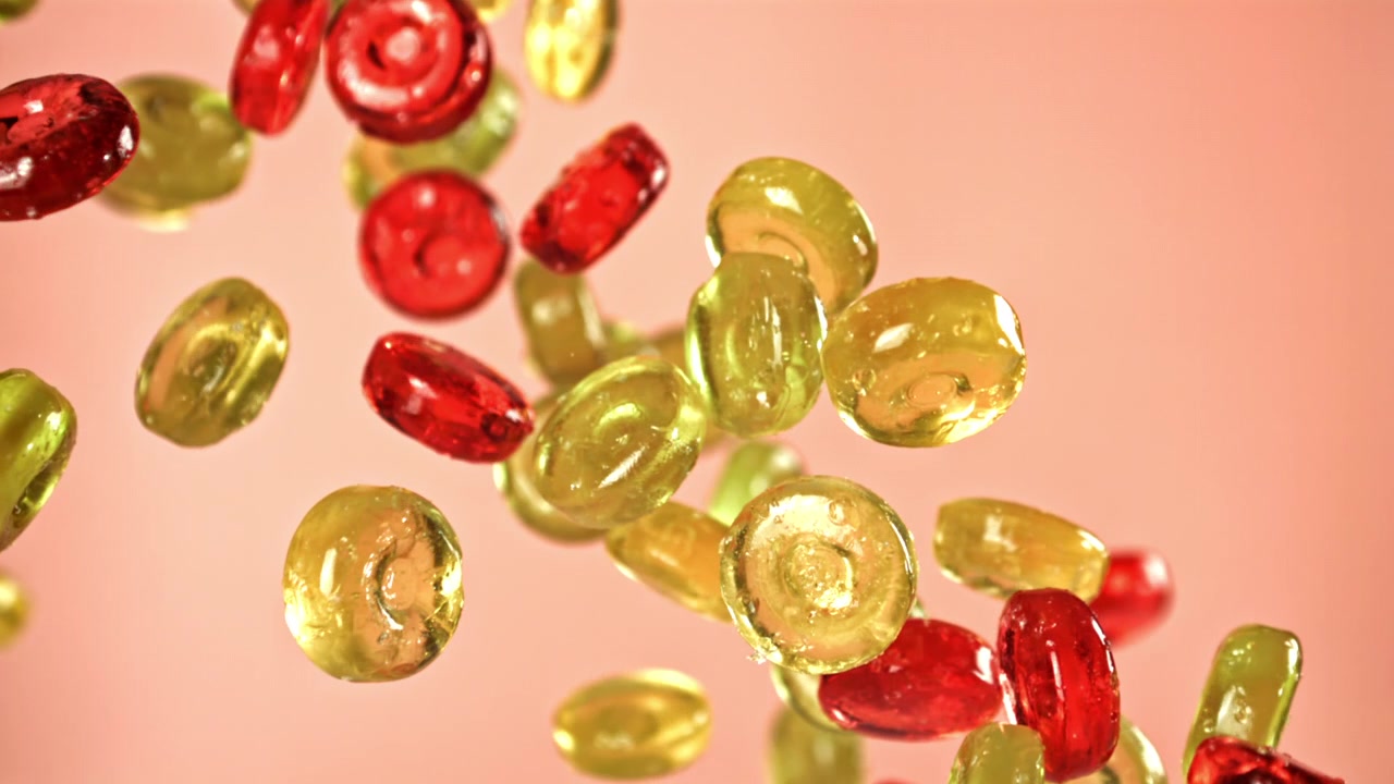 Caramelle colorate che cadono al rallentatore su sfondo rosa