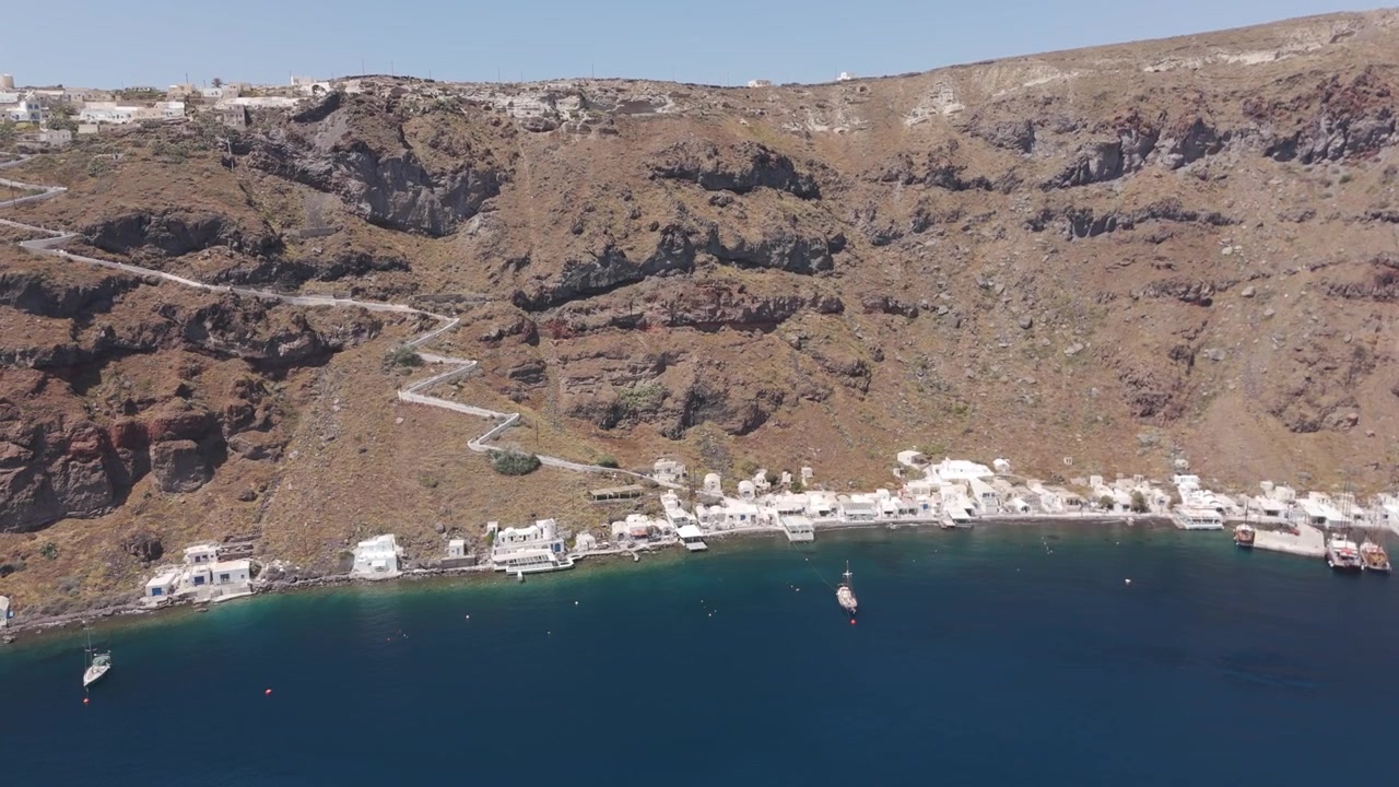 Bela filmagem aérea da ilha vulcânica de Thirasia e seu pequeno porto em Santorini, Grécia. Tomada de dolly circular.