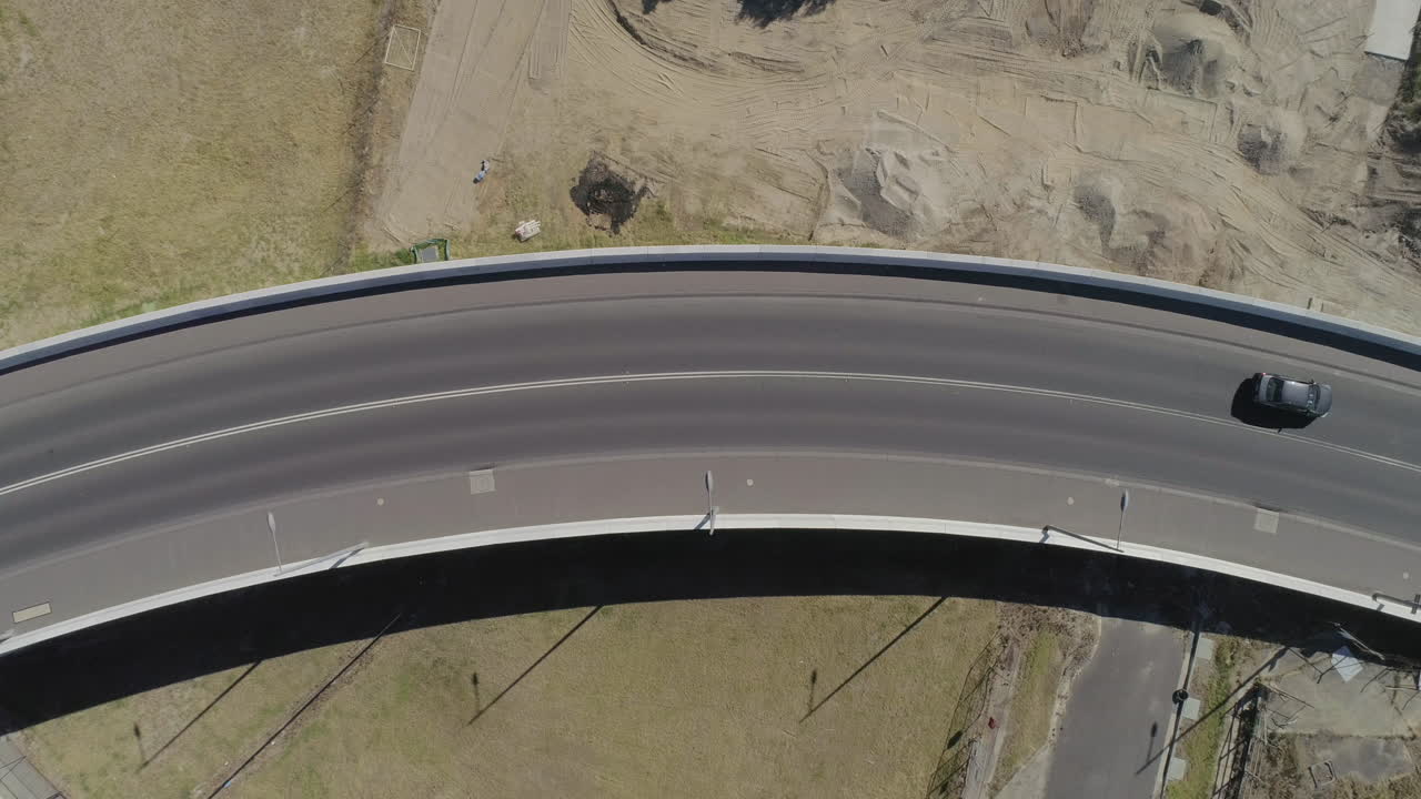 정적 공중 관점에서 프레임 왼쪽에서 오른쪽으로 다리 위를 주행하는 짙은 회색 은색 자동차