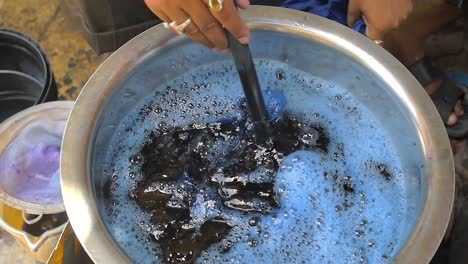 man dyeing clothes blue in street