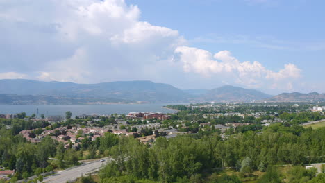 aerial view of kelowna homes in the suburbs on a sunny day, backing up to reveal fields and parks