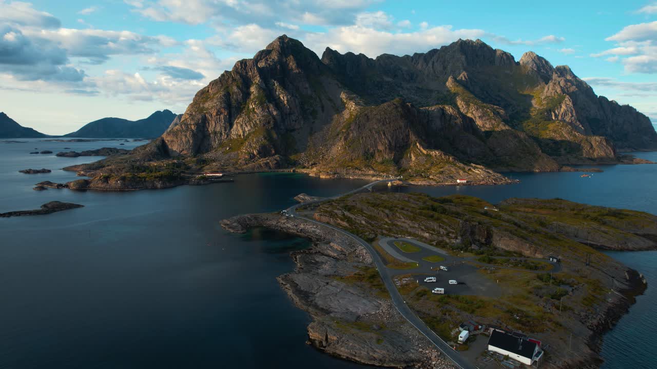 Mountain walls rising above calm Arctic sea islands and villages at Lofoten, Norway. Aerial drone