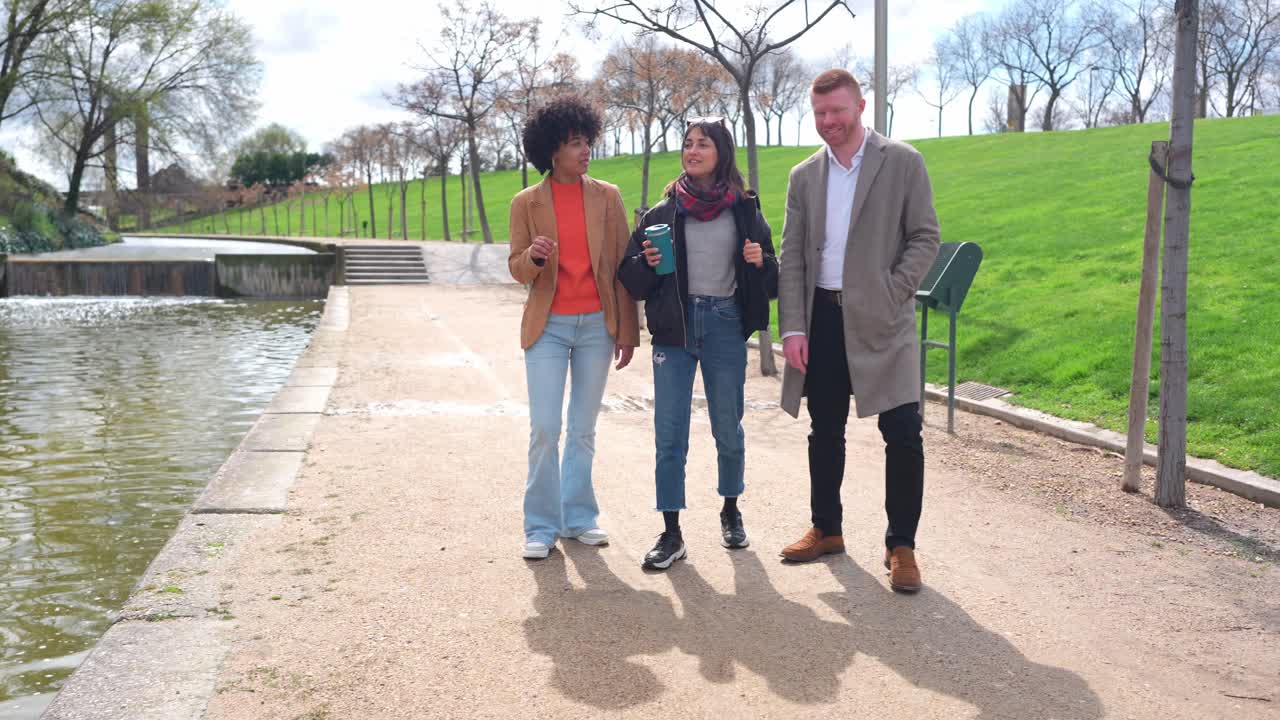 Tre vänner som njuter av en promenad och konversation i parken