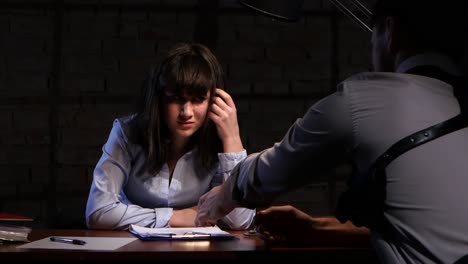 man detective is questioning a suspect in a crime women man detective is questioning a suspect in a crime women tearful girl sits at table in handcuffs man seen from the back in his hands criminal case against the suspect