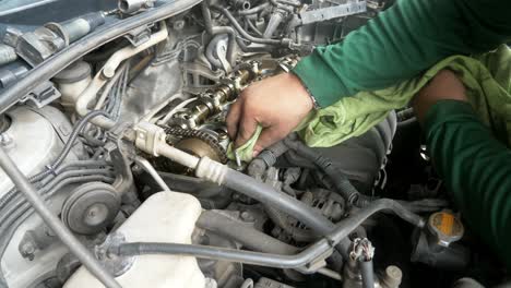 view from the top of a mechanic wiping and removing some dirt from the engine parts of a vehicle