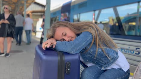 a woman sleeping at a train station. she was tired of waiting for her train. a tourist travels around europe by train. vertical video