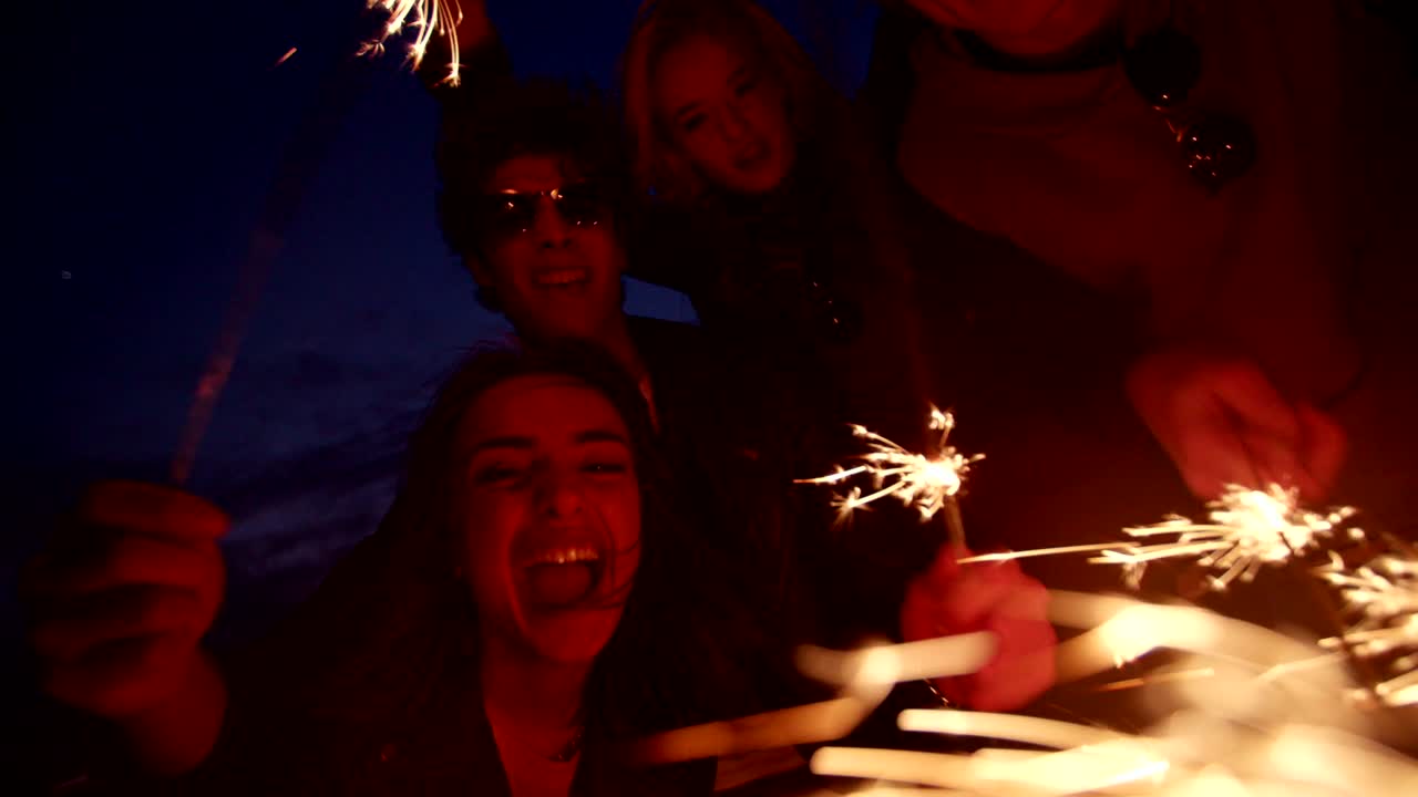 jóvenes amigos hipsters teniendo una fiesta con fuegos artificiales por la noche