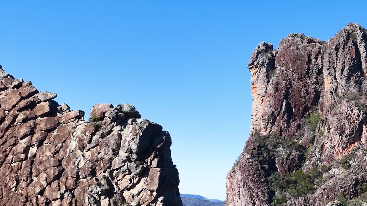 Ujęcie panoramiczne wulkanicznych ścian skalnych pod czystym, błękitnym niebem w Parku Narodowym Warrumbungle w Australii.