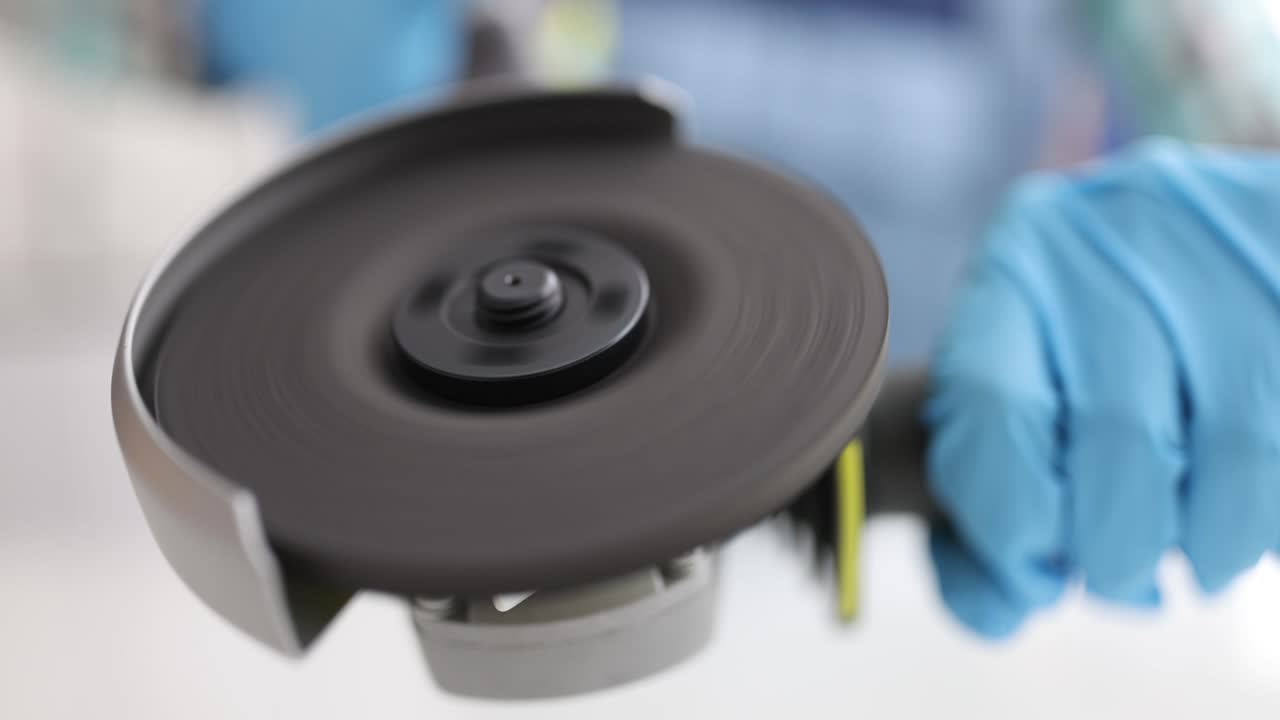 trabajador con guantes sostiene el molinillo con un primer plano del disco